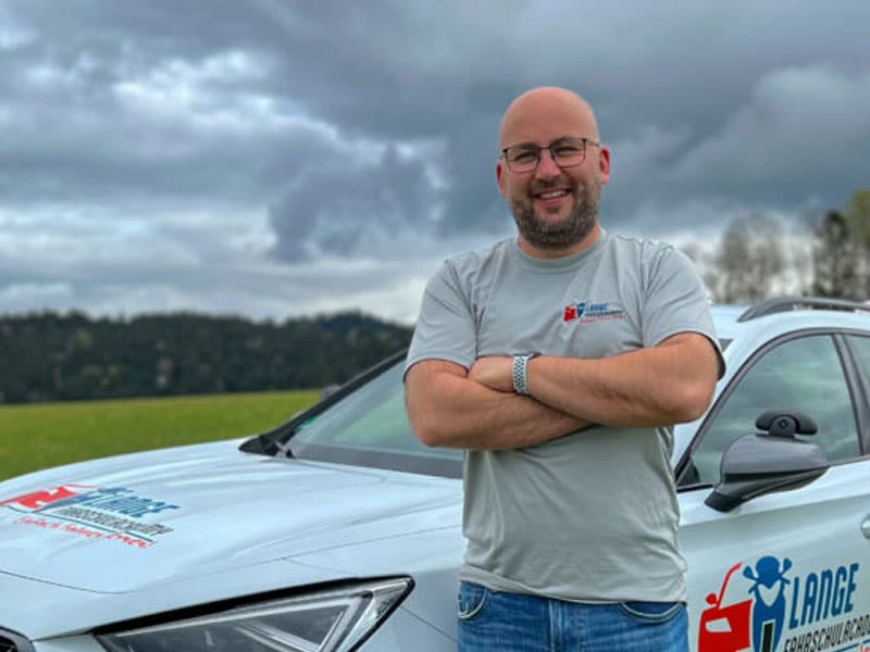 Fahrlehrer Markus Lange vor dem Fahrschulauto der Lange FahrschulAcademy.